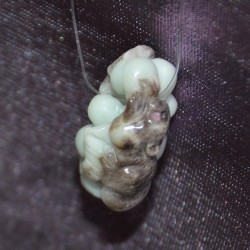 Цайвар ногоон, хар хүрэн өнгө алгалсан амазонит чулуугаар хос навчны хамт боргоцой ба хэрэмийг сийлбэрлэн урласан зүүлт /кулон, гоёл чимэглэл/.